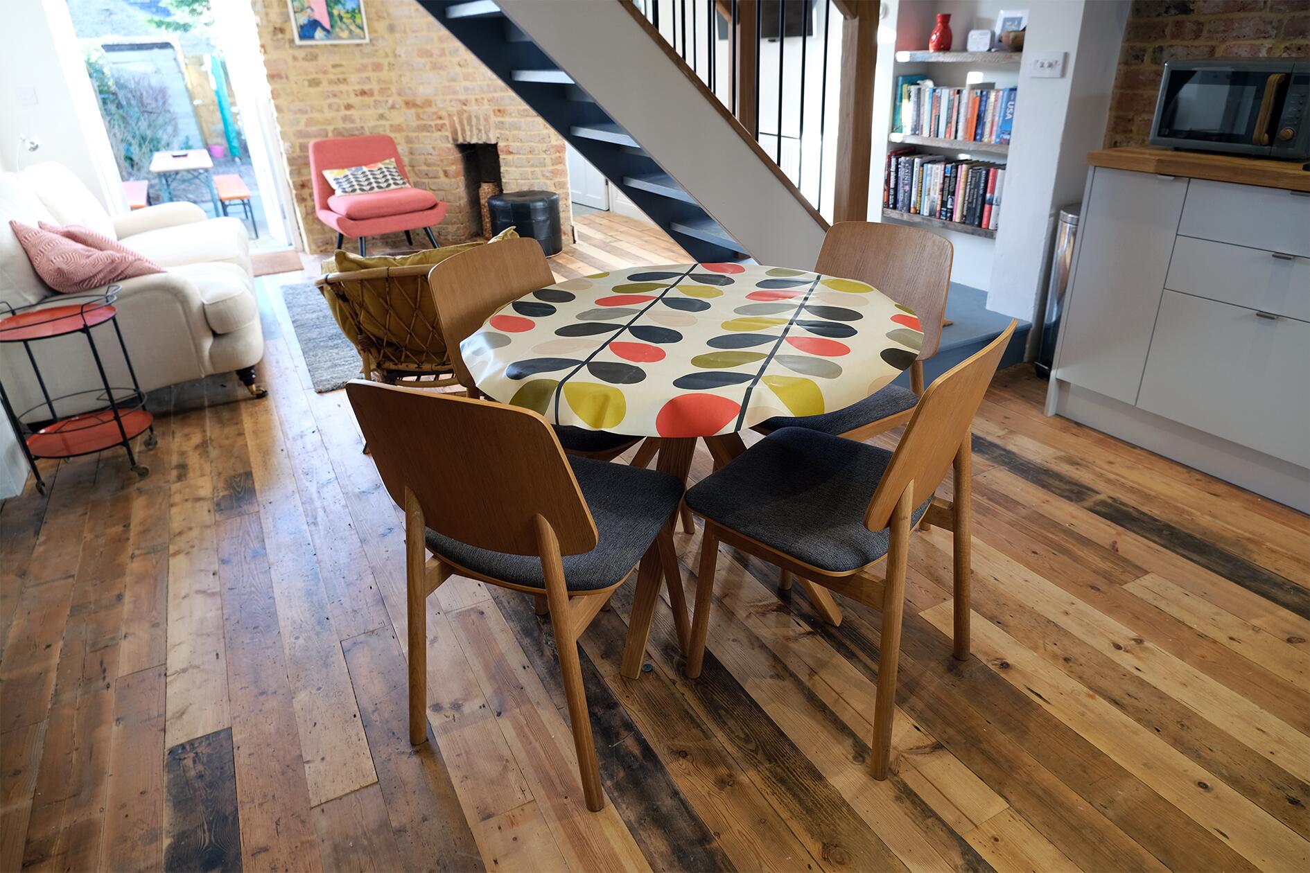 Dining table with a patterned cloth beneath the open staircase