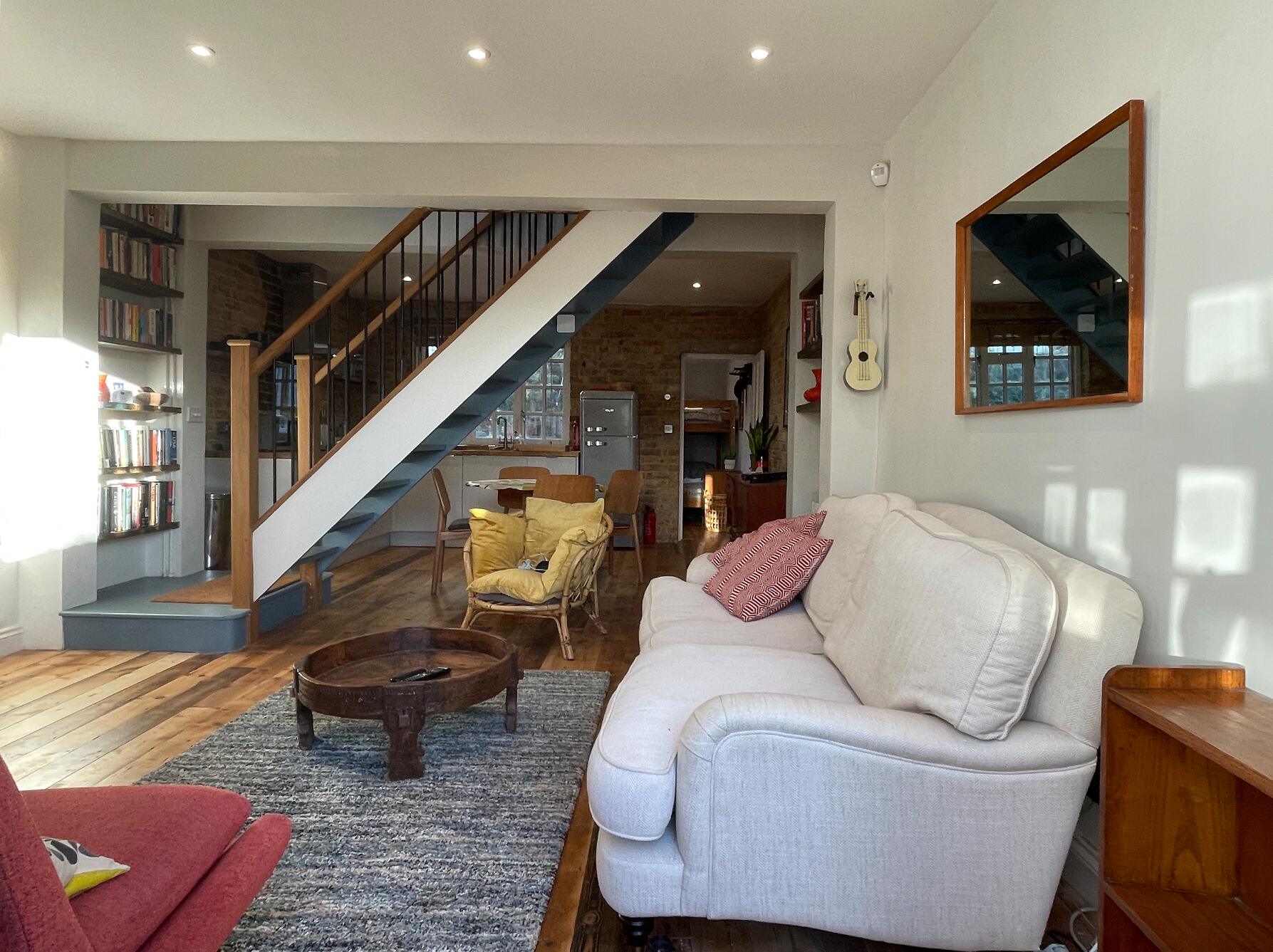 Living room with a white sofa, wooden staircase and exposed brick